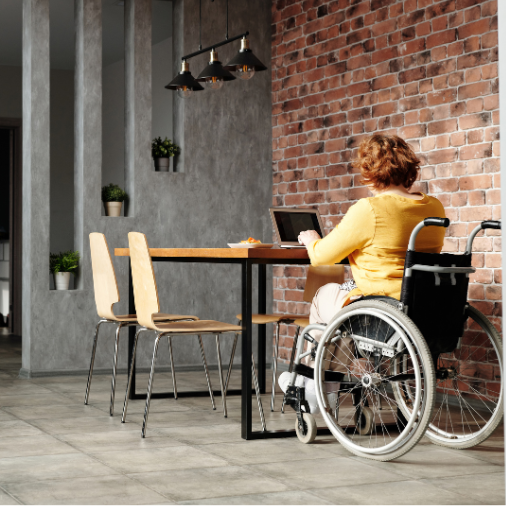 Intérieur d'une salle à manger avec une personne en fauteuil roulant, illustrant l'adaptation de l'habitat pour l'accessibilité.